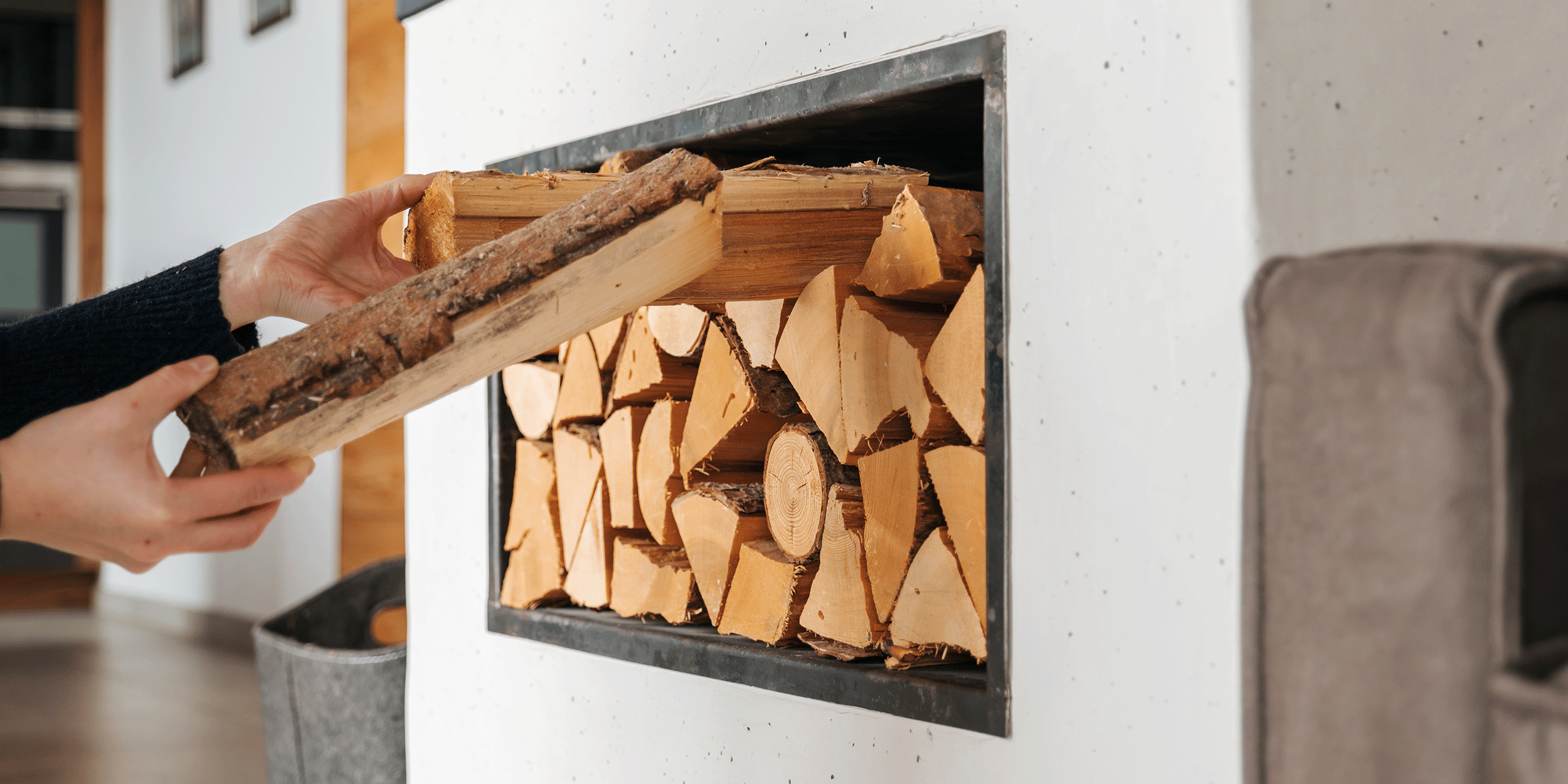 Someone stacking chopped firewood into their indoor storage space